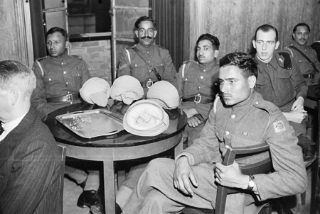 Private Mobed Shaffi of the Royal Indian Army Service Corps (RIASC) listens to the broadcast with some of his fellow soldiers around a table in the Hall of India, 1942